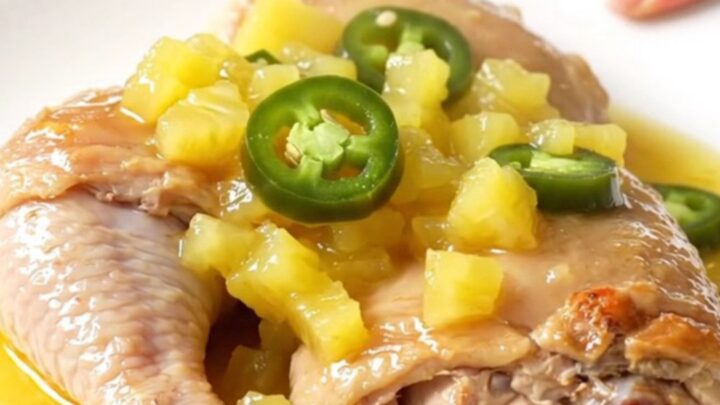 Slow cooker pineapple jalapeno chicken thighs served on a white plate with a glossy pineapple sauce.