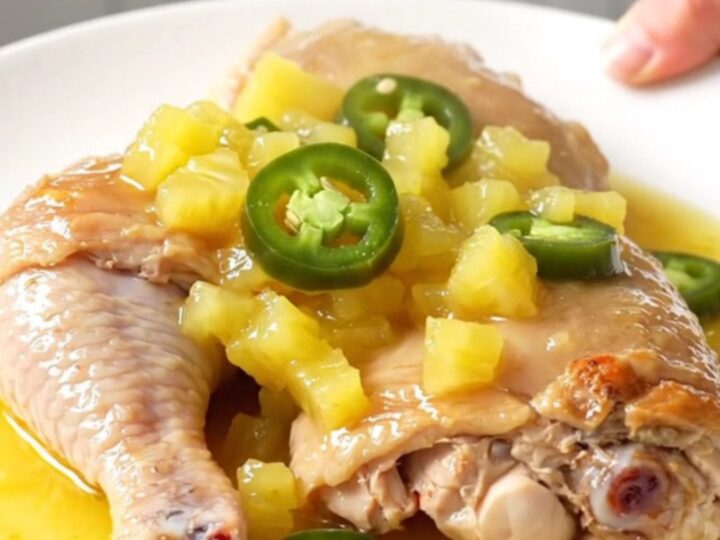 Slow cooker pineapple jalapeno chicken thighs served on a white plate with a glossy pineapple sauce.