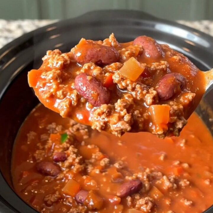 A bowl of hearty beef chili with kidney beans and jalapenos in a slow cooker, featuring a rich red tomato sauce.