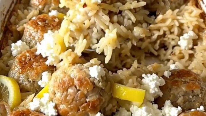 A rustic rectangular ceramic dish filled with golden baked rice, juicy chicken meatballs, and sprinkled feta cheese.