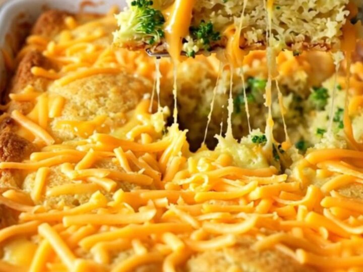 A golden-brown broccoli cheddar cornbread bake in an enameled rectangular dish on a beige countertop.