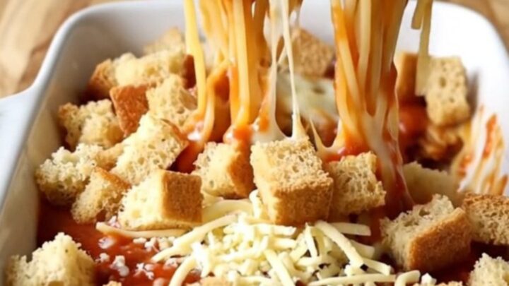 A top-down view of a rectangular baking dish filled with spaghetti in marinara sauce topped with golden garlic bread