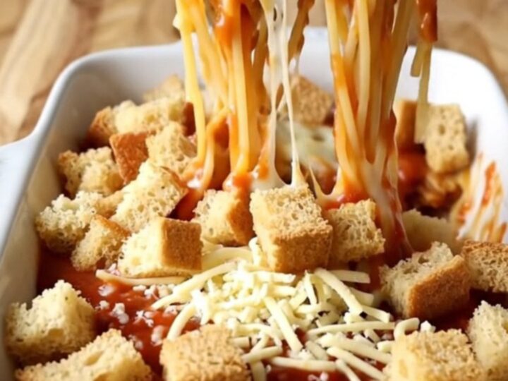 A top-down view of a rectangular baking dish filled with spaghetti in marinara sauce topped with golden garlic bread