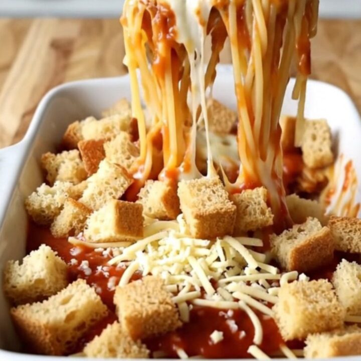 A top-down view of a rectangular baking dish filled with spaghetti in marinara sauce topped with golden garlic bread