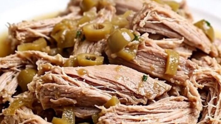 A close-up of tender, shredded pork loin with pickled giardiniera vegetables in a white bowl.