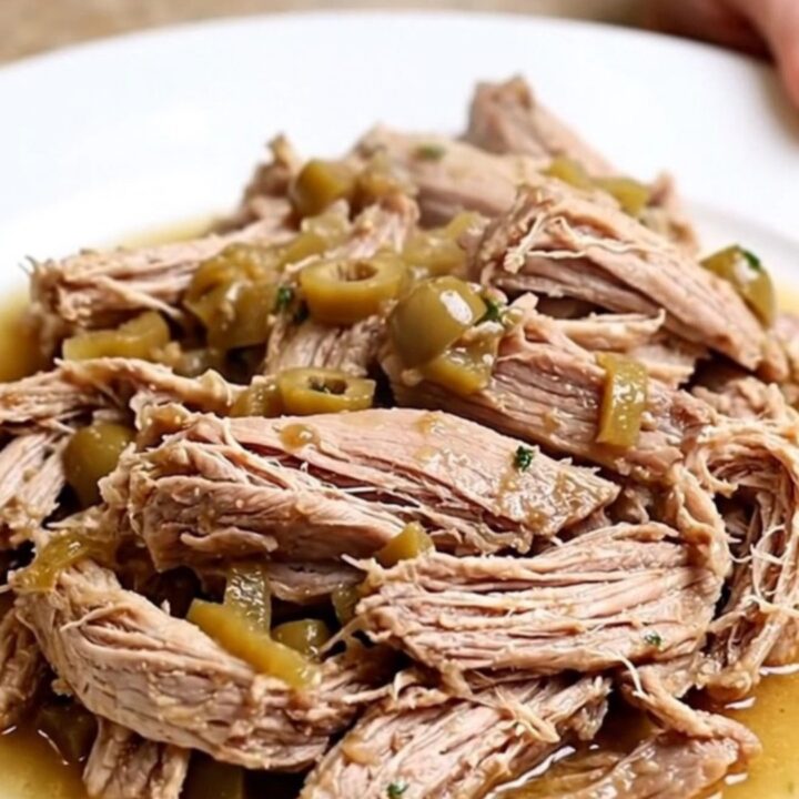 A close-up of tender, shredded pork loin with pickled giardiniera vegetables in a white bowl.