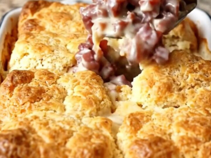 A golden-brown creamed chipped beef biscuit bake in a rectangular white enameled dish.