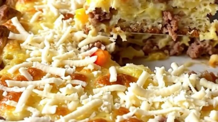 A golden-baked Christmas morning strata in a ceramic dish, featuring sausage, peppers, and melted mozzarella.