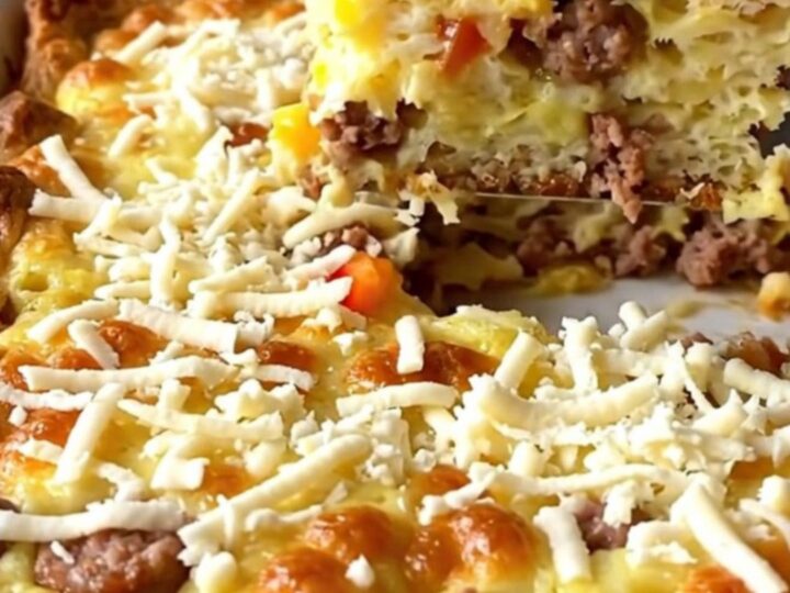 A golden-baked Christmas morning strata in a ceramic dish, featuring sausage, peppers, and melted mozzarella.