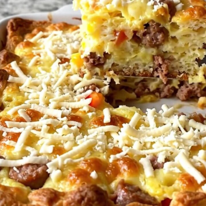 A golden-baked Christmas morning strata in a ceramic dish, featuring sausage, peppers, and melted mozzarella.