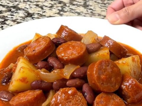 A close-up of a hearty shipwreck dinner with sausage, potatoes, and kidney beans in a thick tomato sauce.