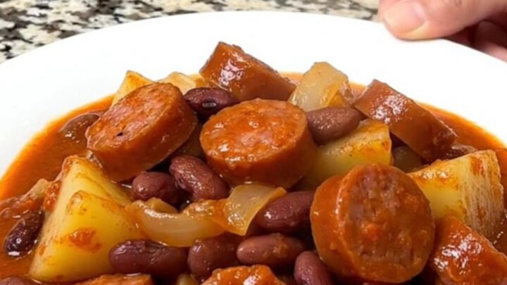 A close-up of a hearty shipwreck dinner with sausage, potatoes, and kidney beans in a thick tomato sauce.