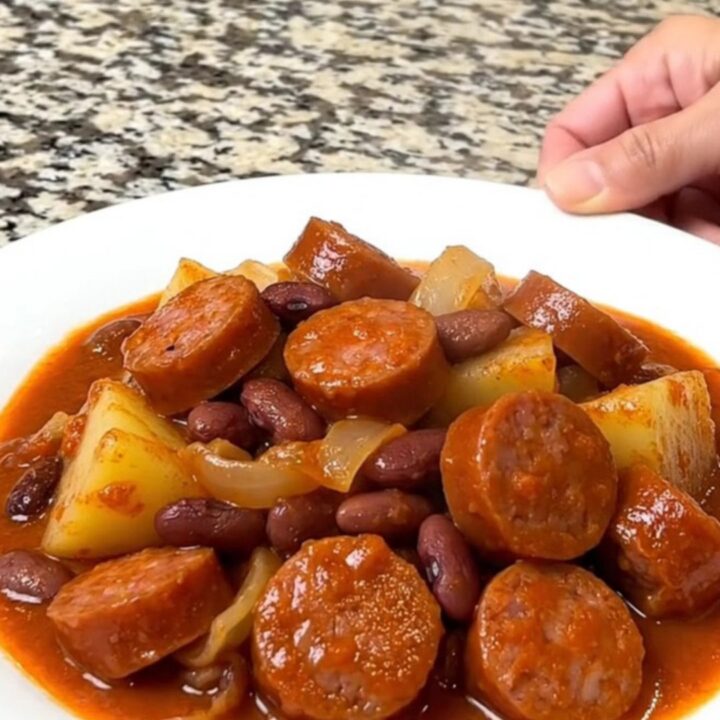 A close-up of a hearty shipwreck dinner with sausage, potatoes, and kidney beans in a thick tomato sauce.