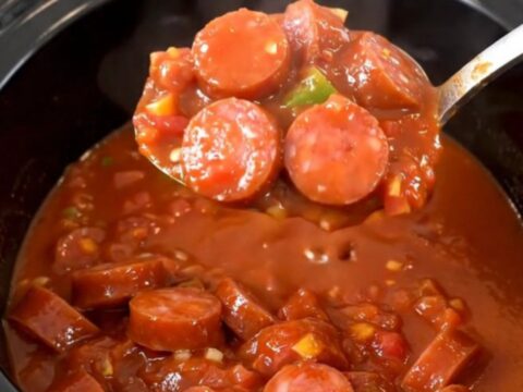 A hearty bowl of smoked sausage and okra stew in a rich tomato sauce, steaming and ready to eat.