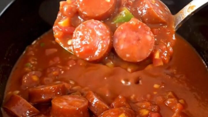A hearty bowl of smoked sausage and okra stew in a rich tomato sauce, steaming and ready to eat.