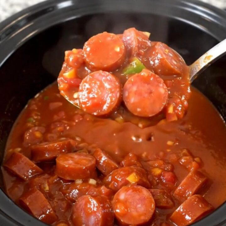 A hearty bowl of smoked sausage and okra stew in a rich tomato sauce, steaming and ready to eat.