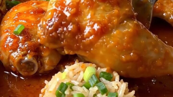 A top-down view of a rectangular baking dish filled with cooked chicken thighs, jasmine rice, and sweet chili sauce.