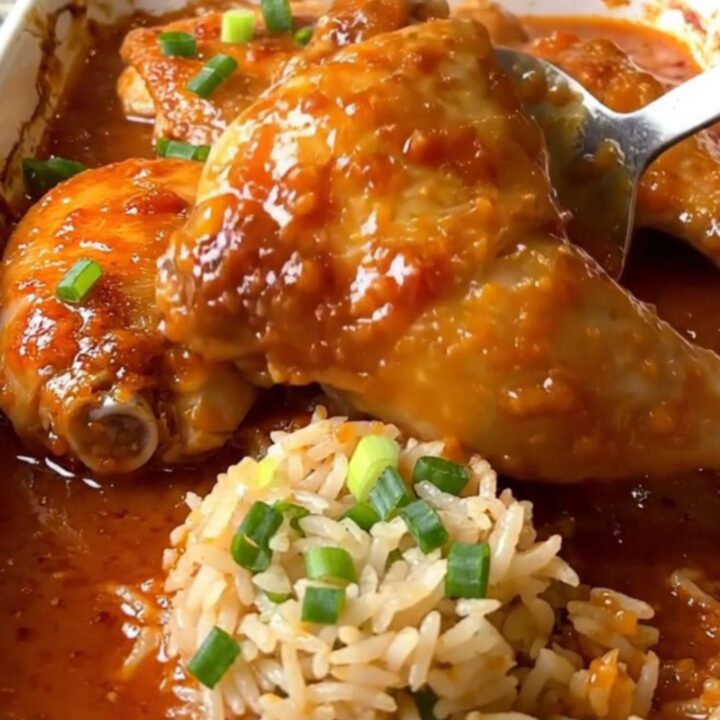 A top-down view of a rectangular baking dish filled with cooked chicken thighs, jasmine rice, and sweet chili sauce.