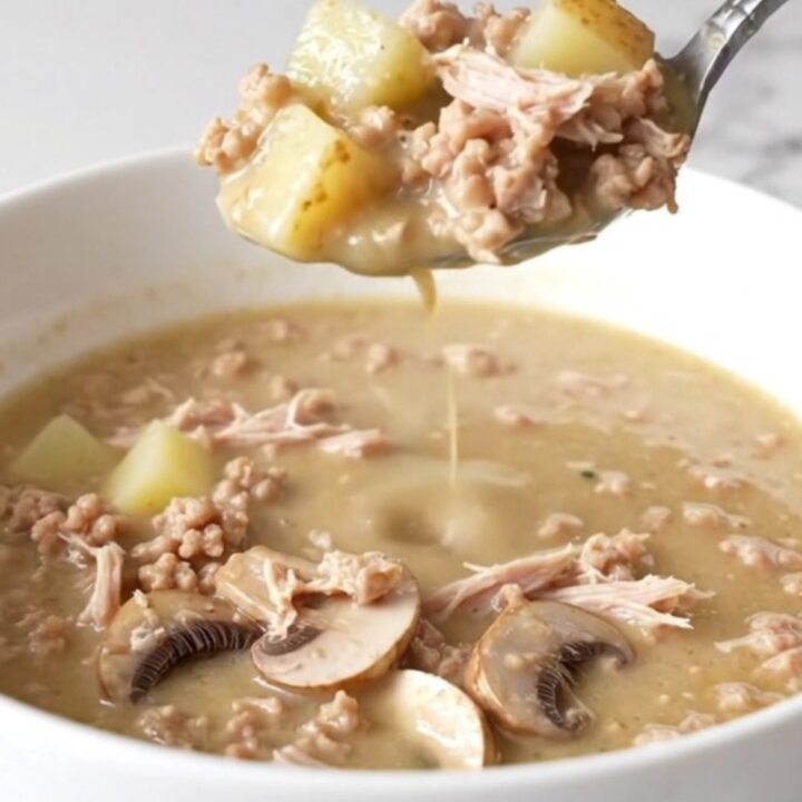 A steaming bowl of creamy mushroom Swiss burger soup with visible chunks of ground turkey, sliced mushrooms