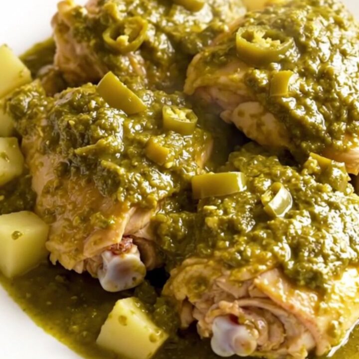 A top-down view of boneless skinless chicken thighs and gold potato cubes in a black slow cooker insert.