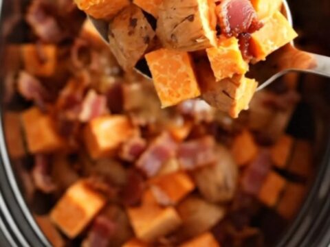 A close-up view of maple bacon sweet potatoes served in a rustic bowl, showing glossy glaze.