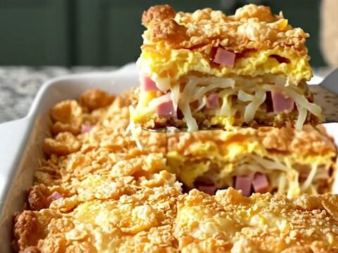 A golden-brown breakfast casserole in a white dish, featuring a crisp cornflake topping.