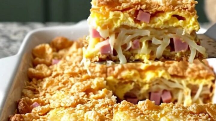 A golden-brown breakfast casserole in a white dish, featuring a crisp cornflake topping.