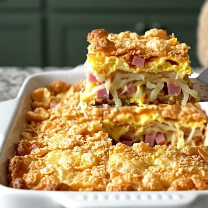 A golden-brown breakfast casserole in a white dish, featuring a crisp cornflake topping.