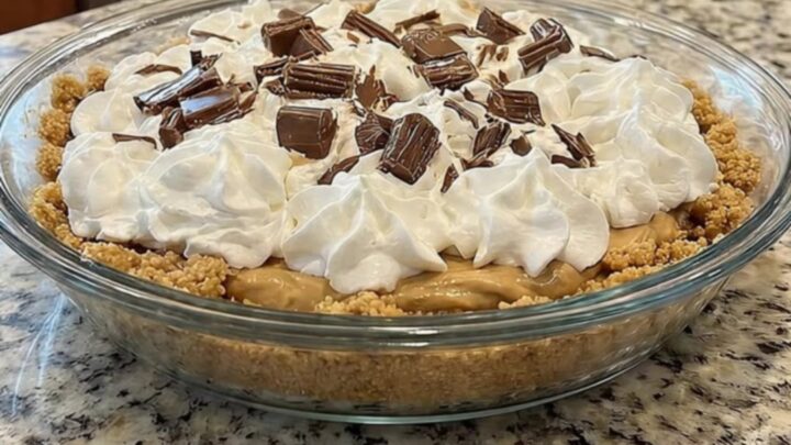 A slice of creamy peanut butter pie with a graham cracker crust and chocolate topping on a granite surface.