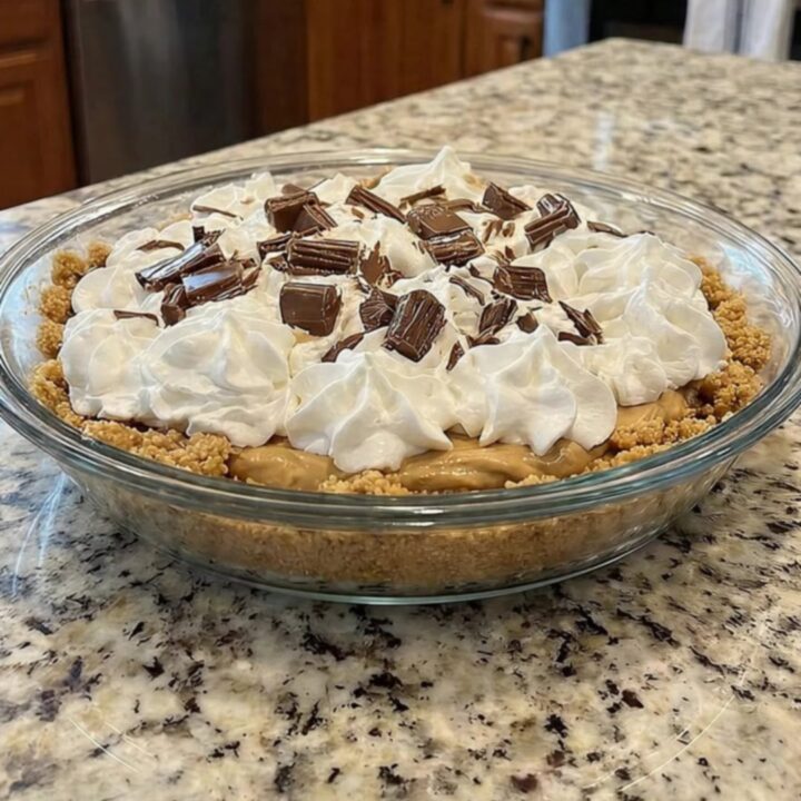 A slice of creamy peanut butter pie with a graham cracker crust and chocolate topping on a granite surface.