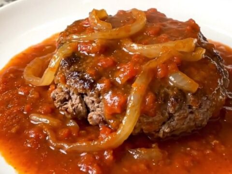 A rustic slow cooker filled with tender hamburger steaks smothered in a rich tomato and onion gravy.