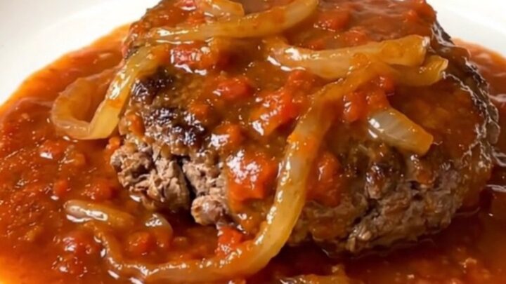 A rustic slow cooker filled with tender hamburger steaks smothered in a rich tomato and onion gravy.