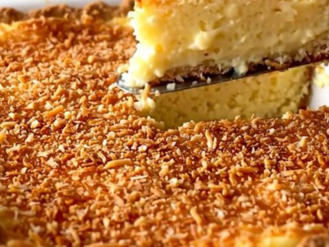 A top-down view of a creamy coconut custard pie in a white ceramic dish with a golden toasted coconut top.