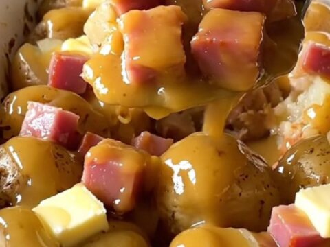 A top-down view of a ceramic baking dish filled with halved baby gold potatoes and cubed ham.