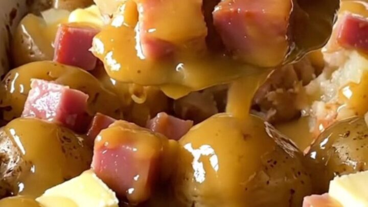 A top-down view of a ceramic baking dish filled with halved baby gold potatoes and cubed ham.