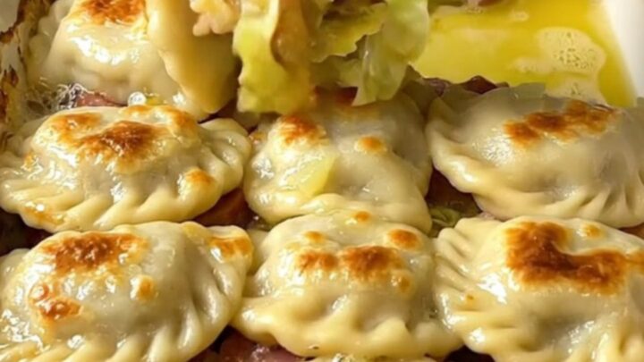 A golden, crispy pierogi-topped cabbage and kielbasa bake in a rectangular ceramic dish.