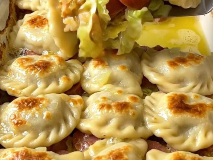 A golden, crispy pierogi-topped cabbage and kielbasa bake in a rectangular ceramic dish.