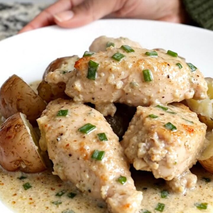 A close-up of creamy chive chicken and tender baby potatoes served on a white plate.