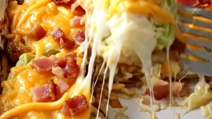 A rectangular ceramic dish filled with golden-brown baked cabbage wedges topped with melted cheddar and crispy bacon.