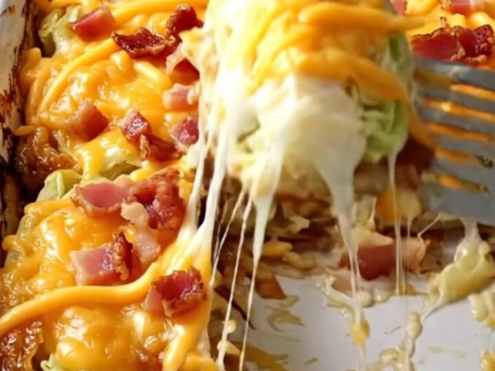A rectangular ceramic dish filled with golden-brown baked cabbage wedges topped with melted cheddar and crispy bacon.
