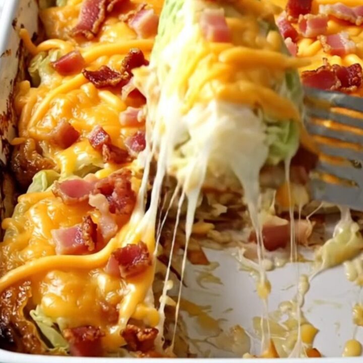 A rectangular ceramic dish filled with golden-brown baked cabbage wedges topped with melted cheddar and crispy bacon.