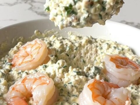 A top-down view of a black slow cooker filled with creamy garlic parmesan shrimp scampi dip.