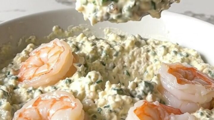A top-down view of a black slow cooker filled with creamy garlic parmesan shrimp scampi dip.