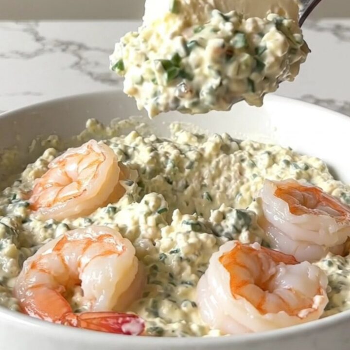 A top-down view of a black slow cooker filled with creamy garlic parmesan shrimp scampi dip.