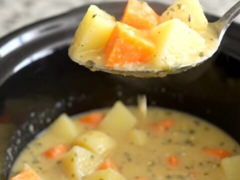 A close-up view of the creamy root vegetable chowder in a slow cooker insert.
