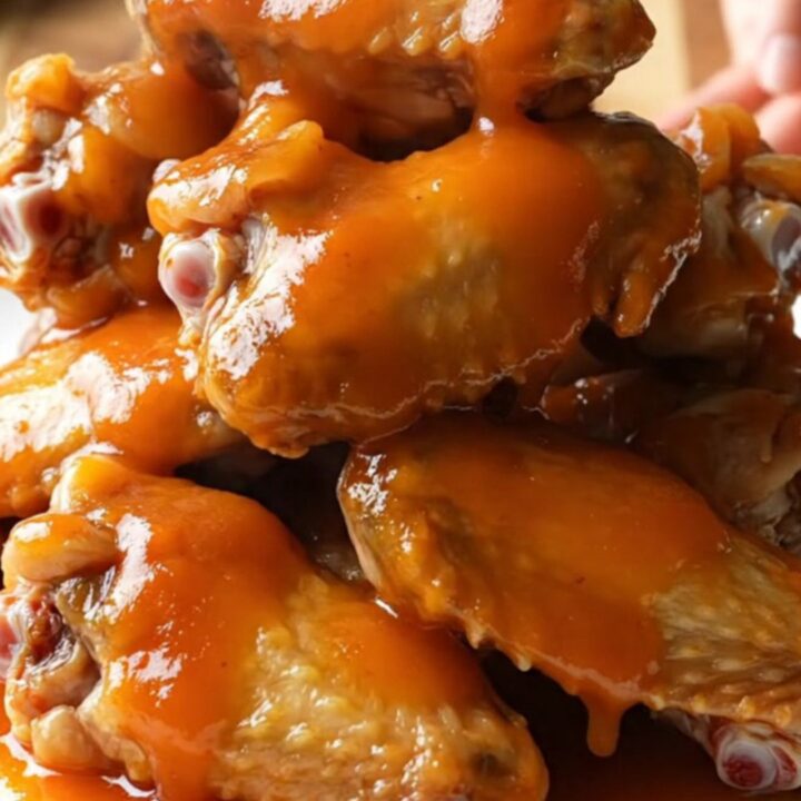 A close-up view of slow-cooked apricot sriracha chicken wings served on a white plate.