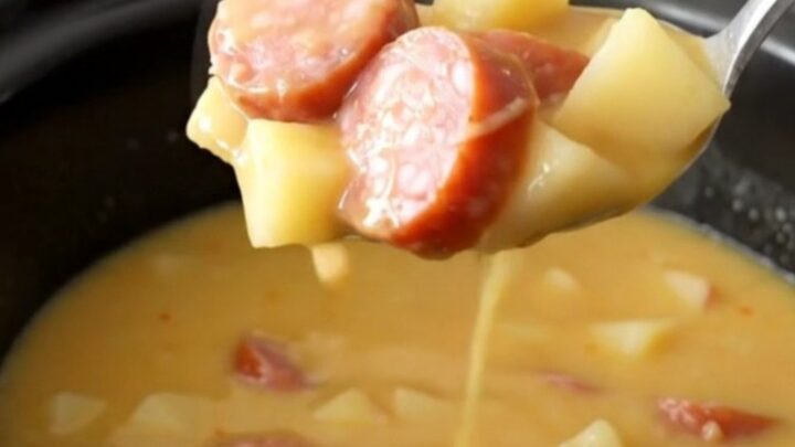 A bowl of creamy Crockpot Smoked Sausage Apple Cheddar Chowder with visible sausage coins and potato cubes.