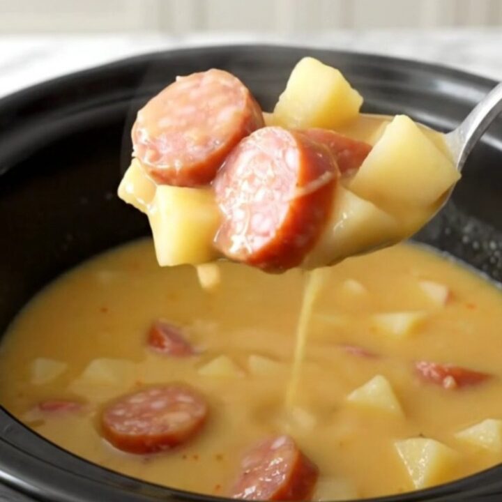 A bowl of creamy Crockpot Smoked Sausage Apple Cheddar Chowder with visible sausage coins and potato cubes.