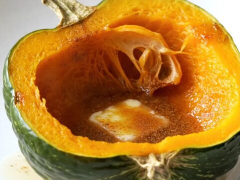 Two halves of acorn squash in a slow cooker topped with butter, brown sugar, and cinnamon.