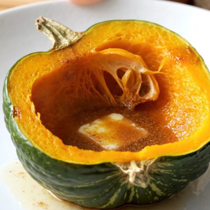 Two halves of acorn squash in a slow cooker topped with butter, brown sugar, and cinnamon.